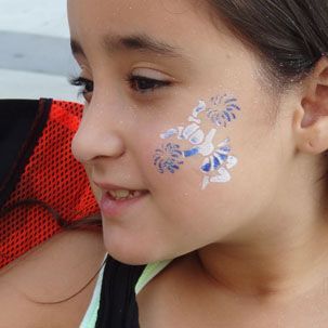 A close up of a young girl with flowers painted on her face.