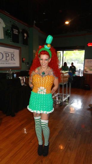 A woman in a balloon costume is standing on a wooden floor.