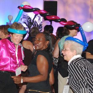 A group of people are dancing with balloons on their heads