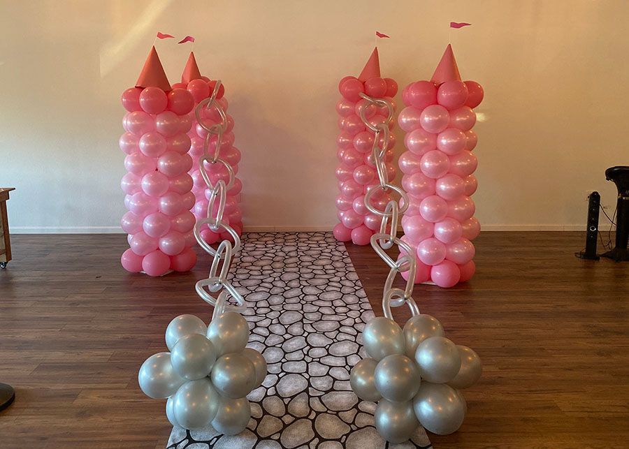 A room decorated with pink and silver balloons in the shape of castles.