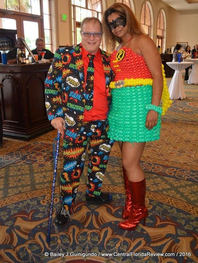 A man in a suit and a woman in a balloon dress pose for a picture