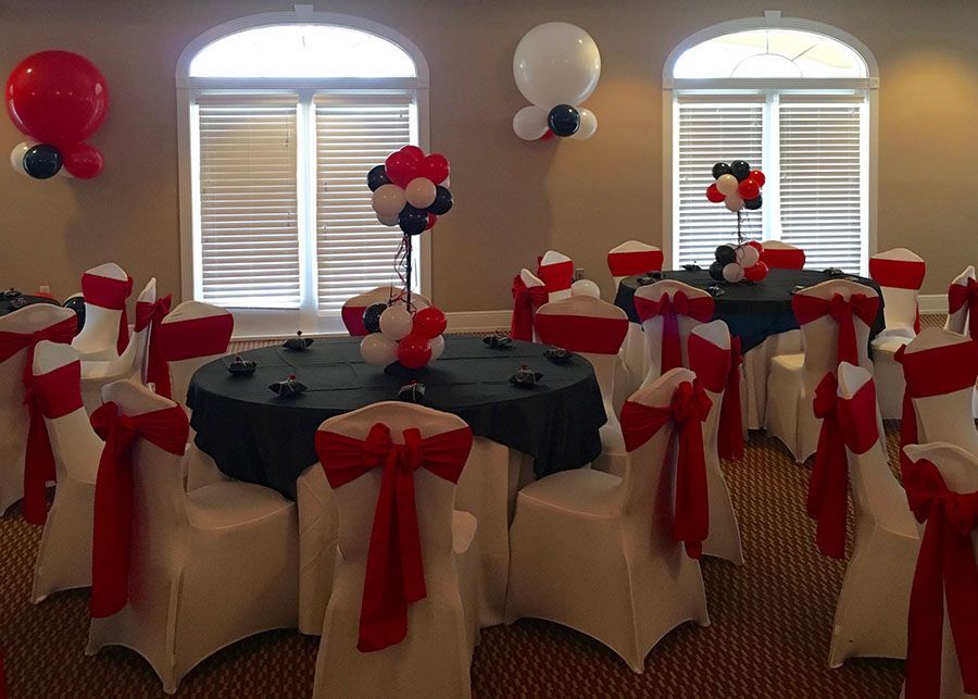 A room with tables and chairs decorated with red , white and blue balloons.