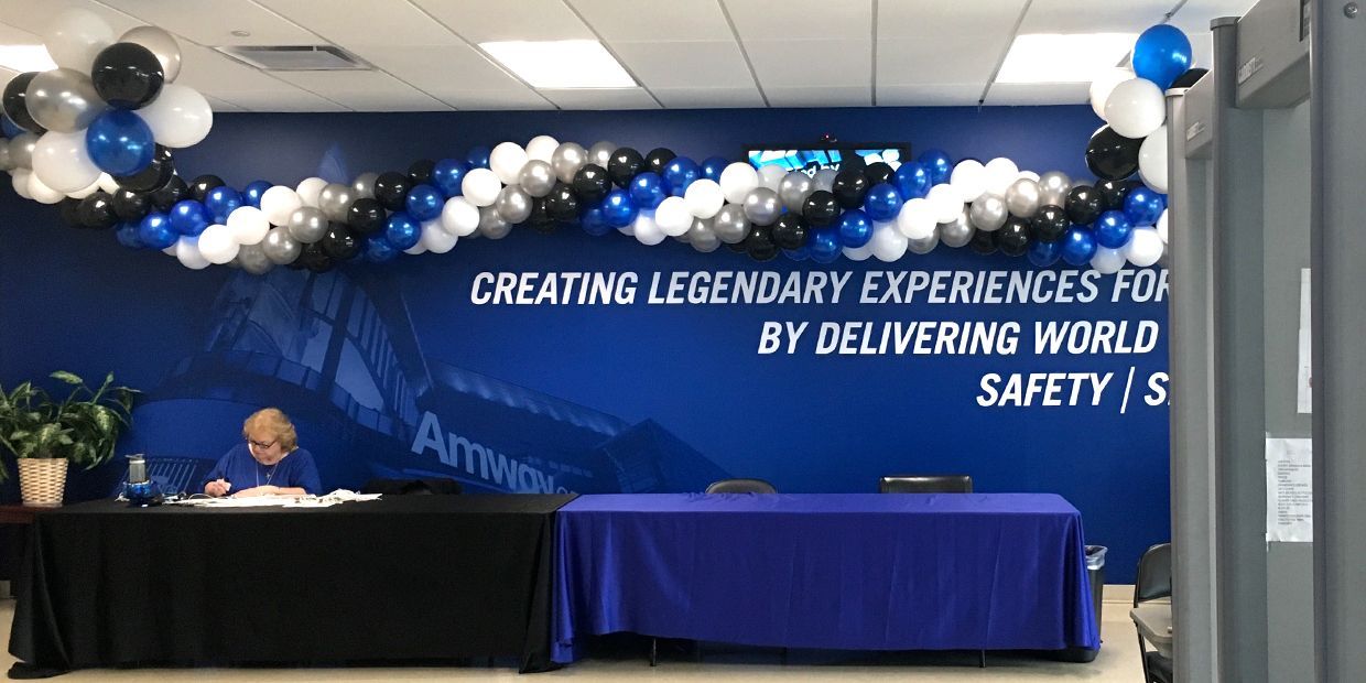 A man is sitting at a desk in front of a sign that says creating legendary experiences by delivering world safety.