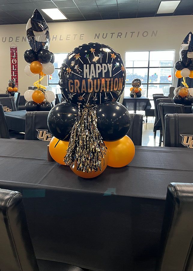 A table is decorated with balloons and a balloon that says `` happy graduation ''.