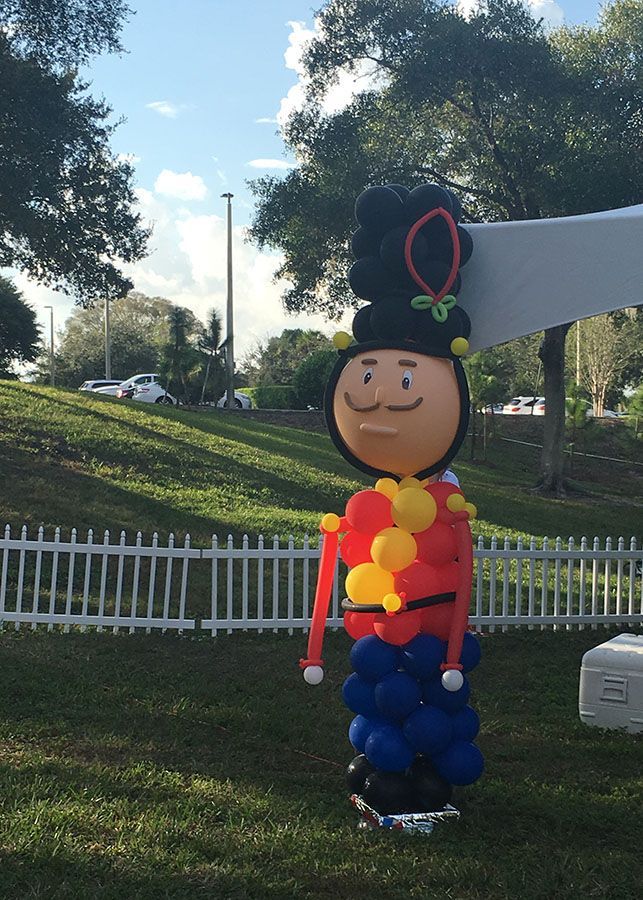 A toy soldier made out of balloons is standing in the grass
