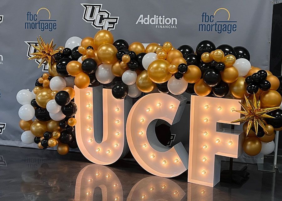 The word ucf is surrounded by balloons and lights.