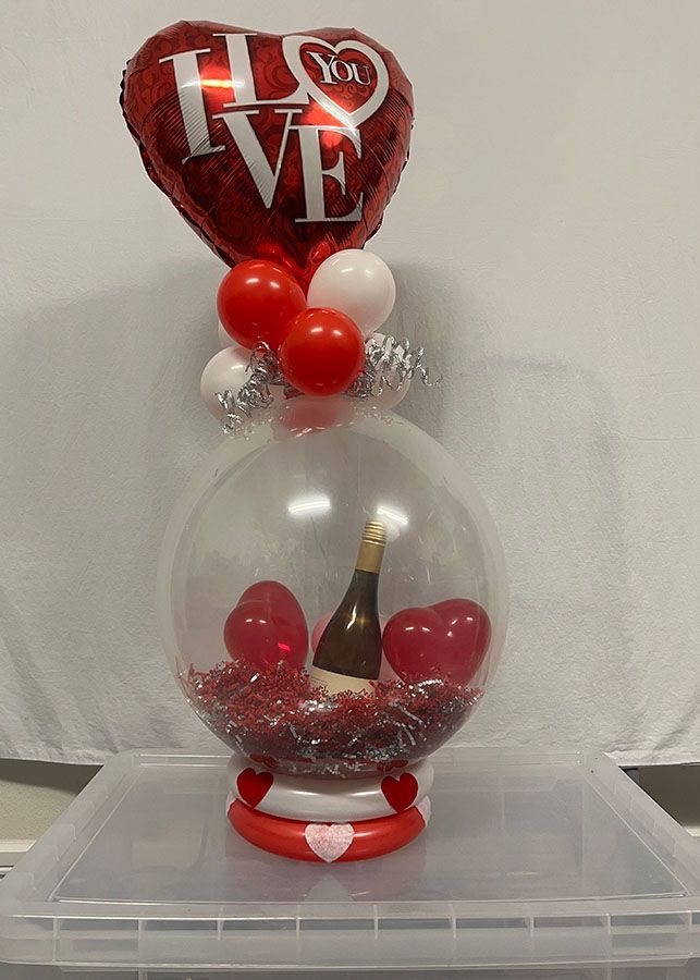 A balloon filled with hearts and a bottle of wine.
