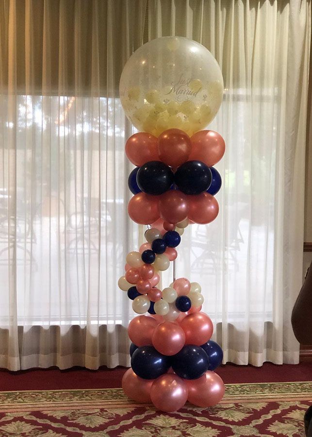 A balloon tower is sitting in front of a window in a room.