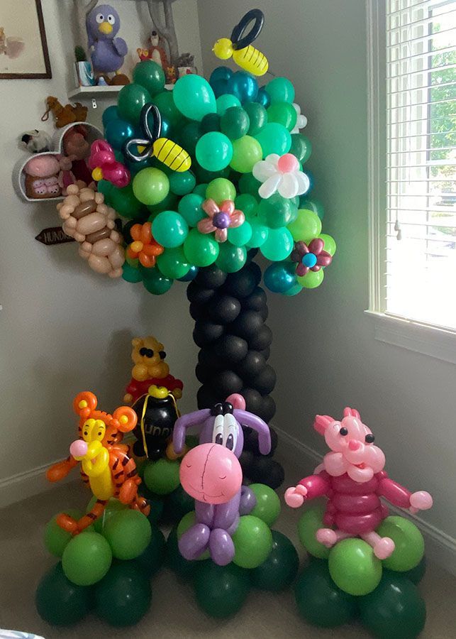 A room filled with balloons shaped like animals and a tree.
