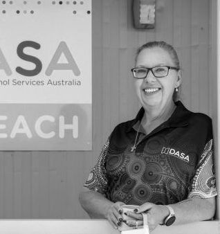A woman wearing glasses is standing in front of a sign.