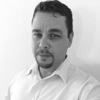 A man with a beard is smiling in a black and white photo.