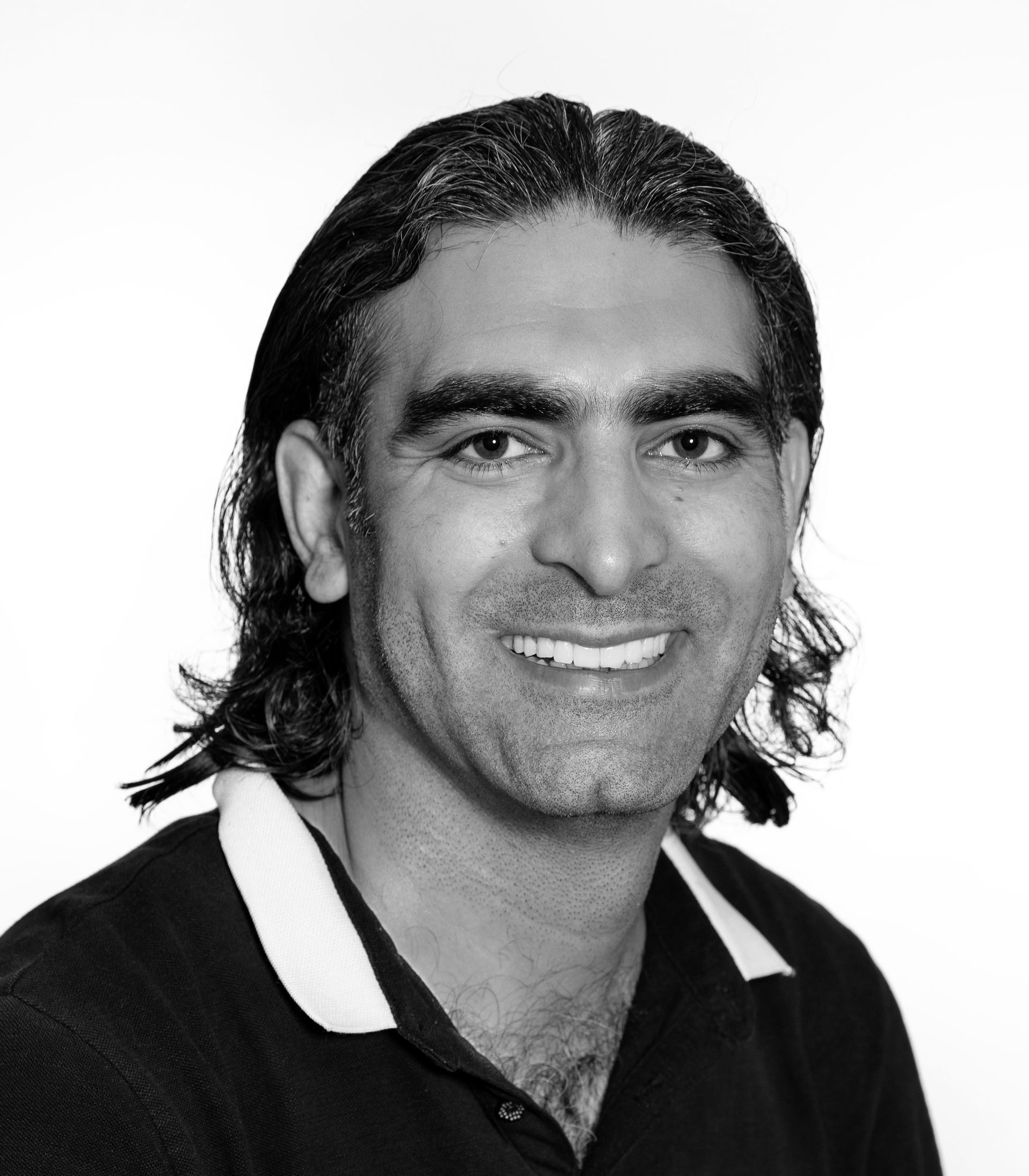 A man with white hair is smiling in a black and white photo.