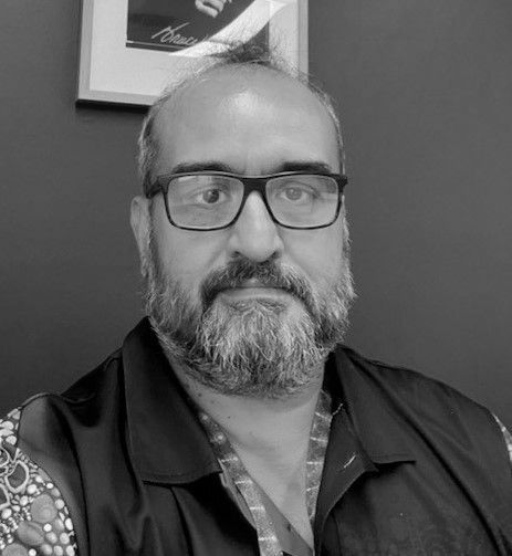 A man with a beard and glasses is wearing a black shirt.