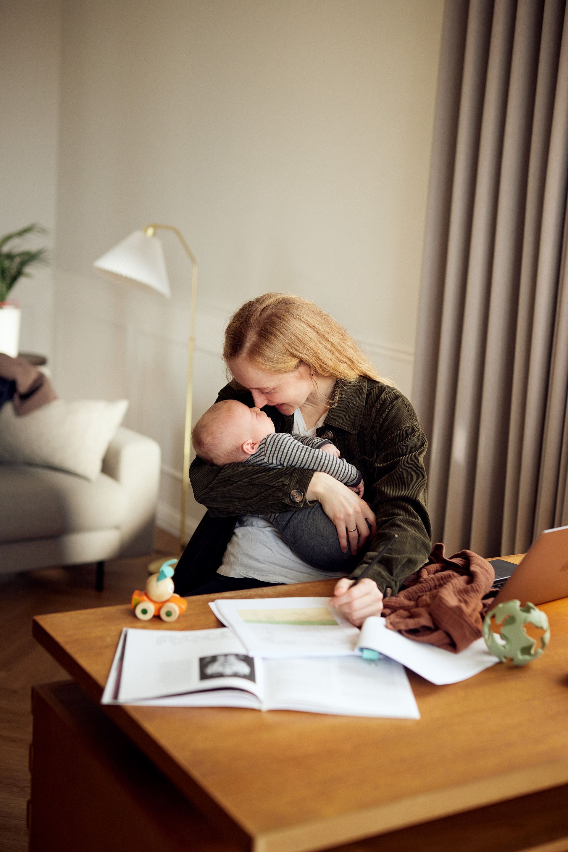 Une femme tient un bébé alors qu'elle est assise à une table.