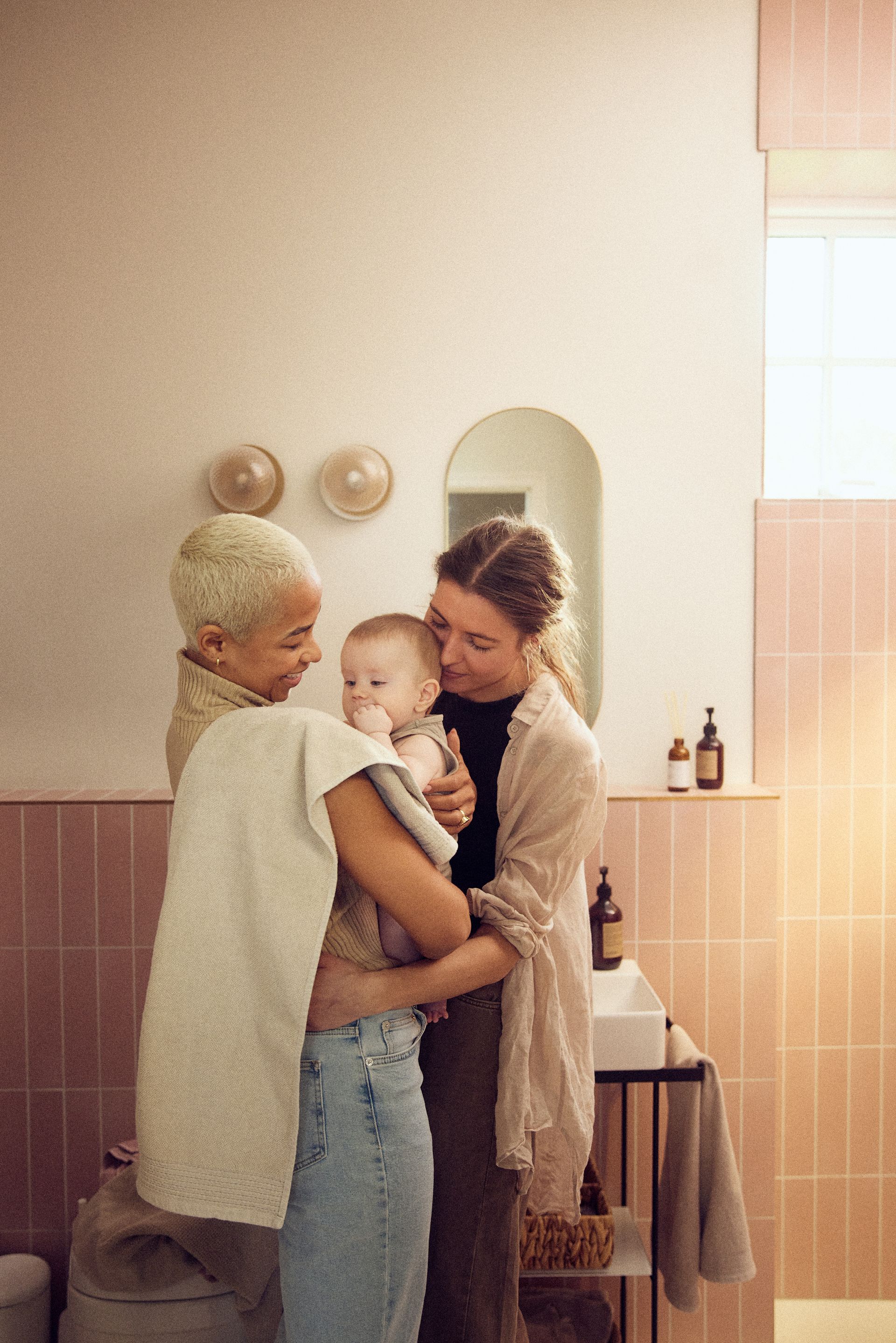 Deux femmes tiennent un bébé dans une salle de bain.