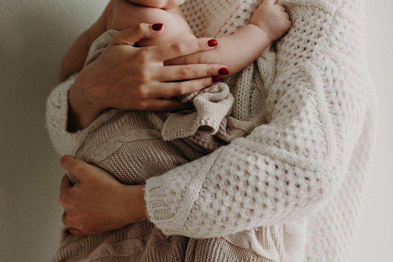 A woman is holding a baby in her arms.