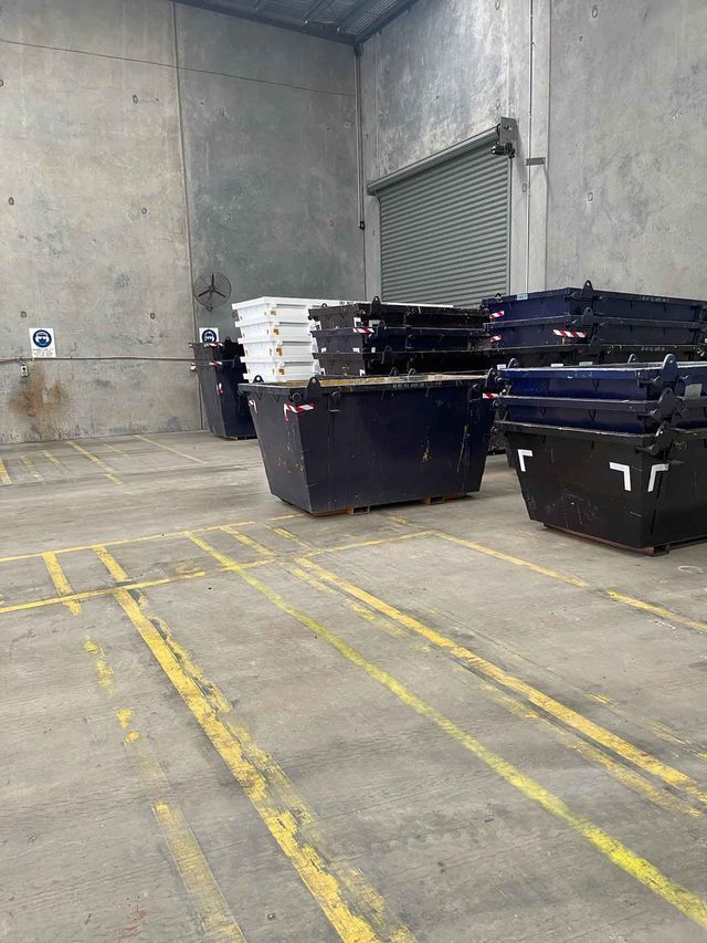 A warehouse filled with lots of dumpsters stacked on top of each other.