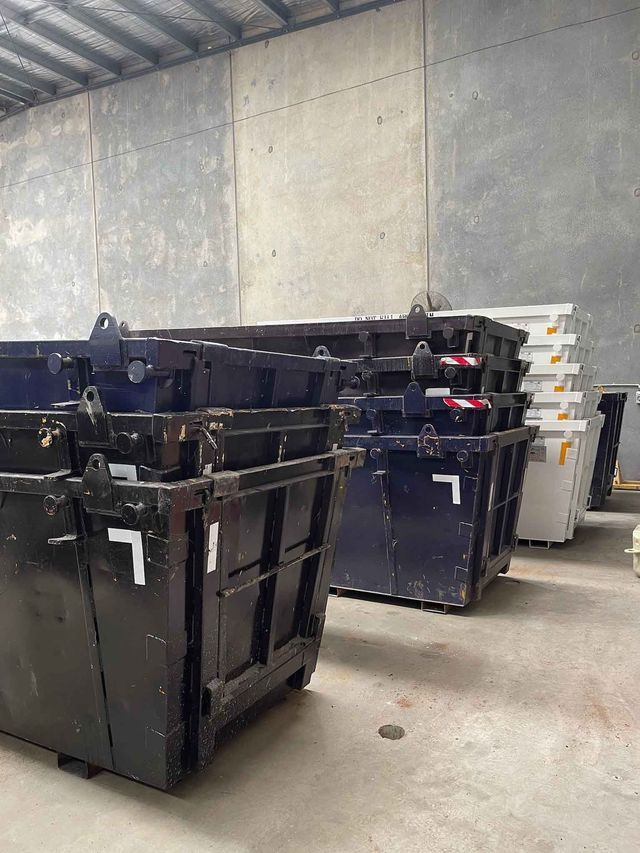 A row of dumpsters are stacked on top of each other in a warehouse.