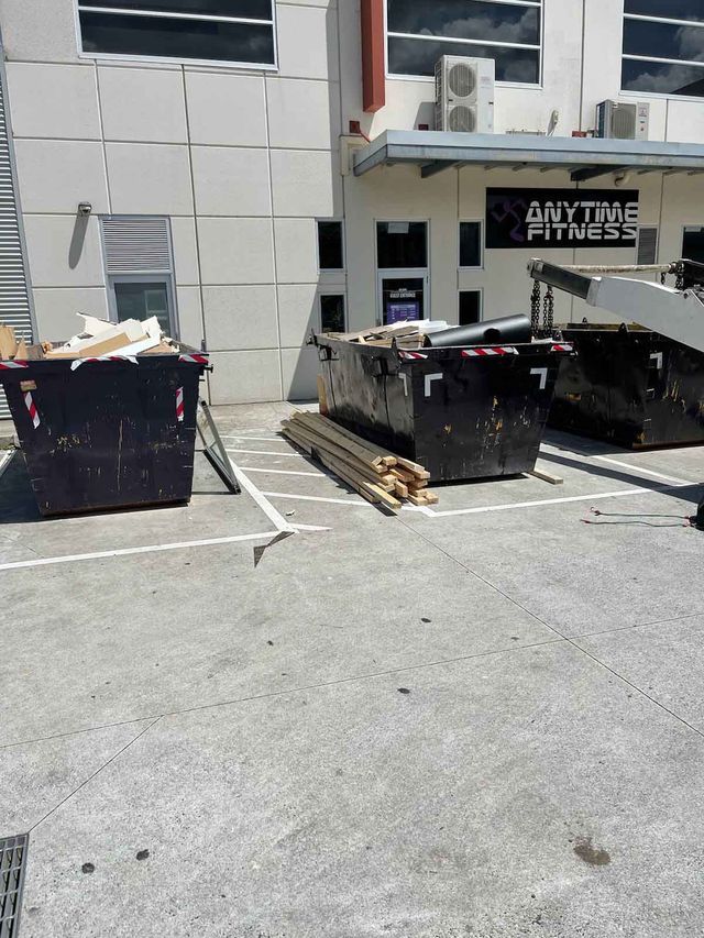 A dumpster is sitting in a parking lot in front of a building.