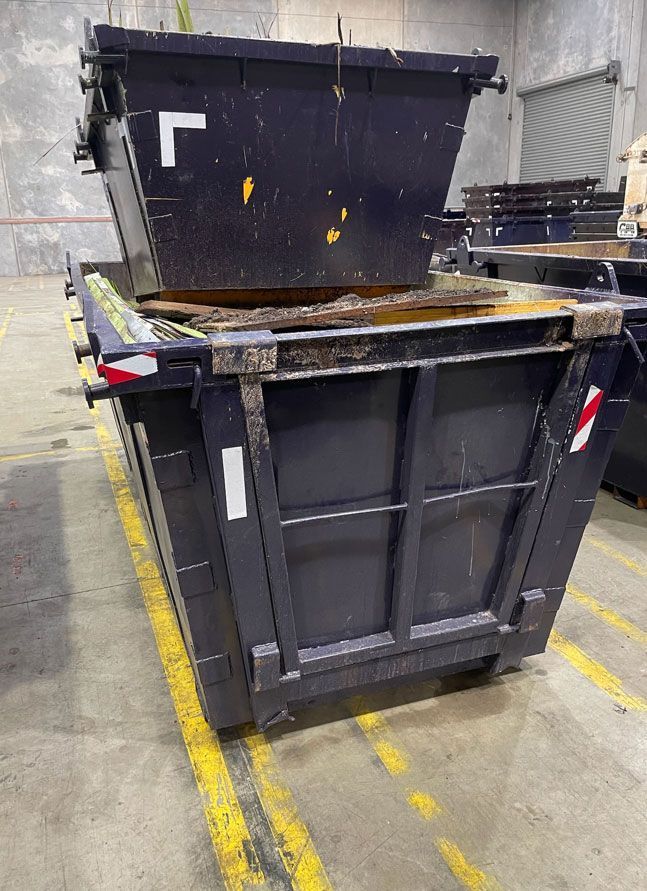 A dumpster is sitting on top of another dumpster in a warehouse.