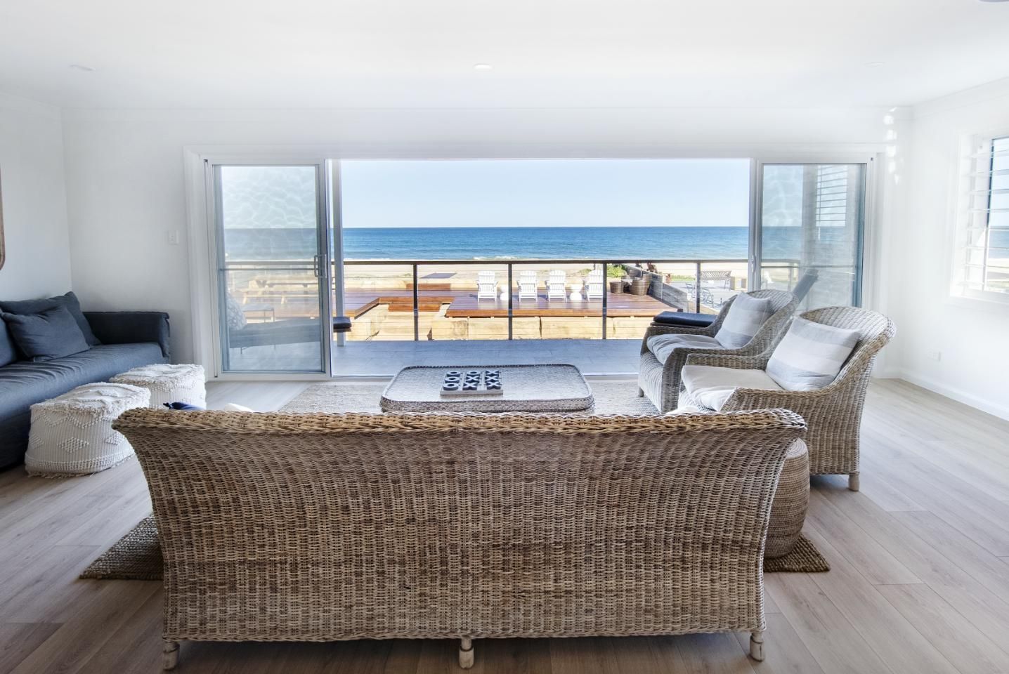 Living room with wicker furniture, large window overlooking the ocean.