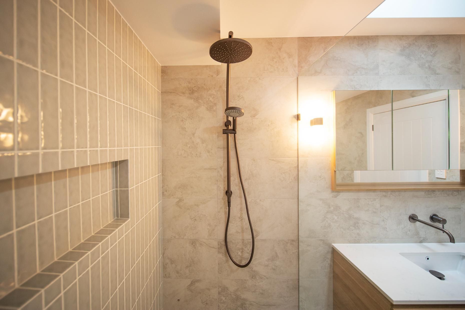 A Bathroom With a Shower , Sink and Mirror — Beach Breeze Building In Tumbi Umbi, NSW