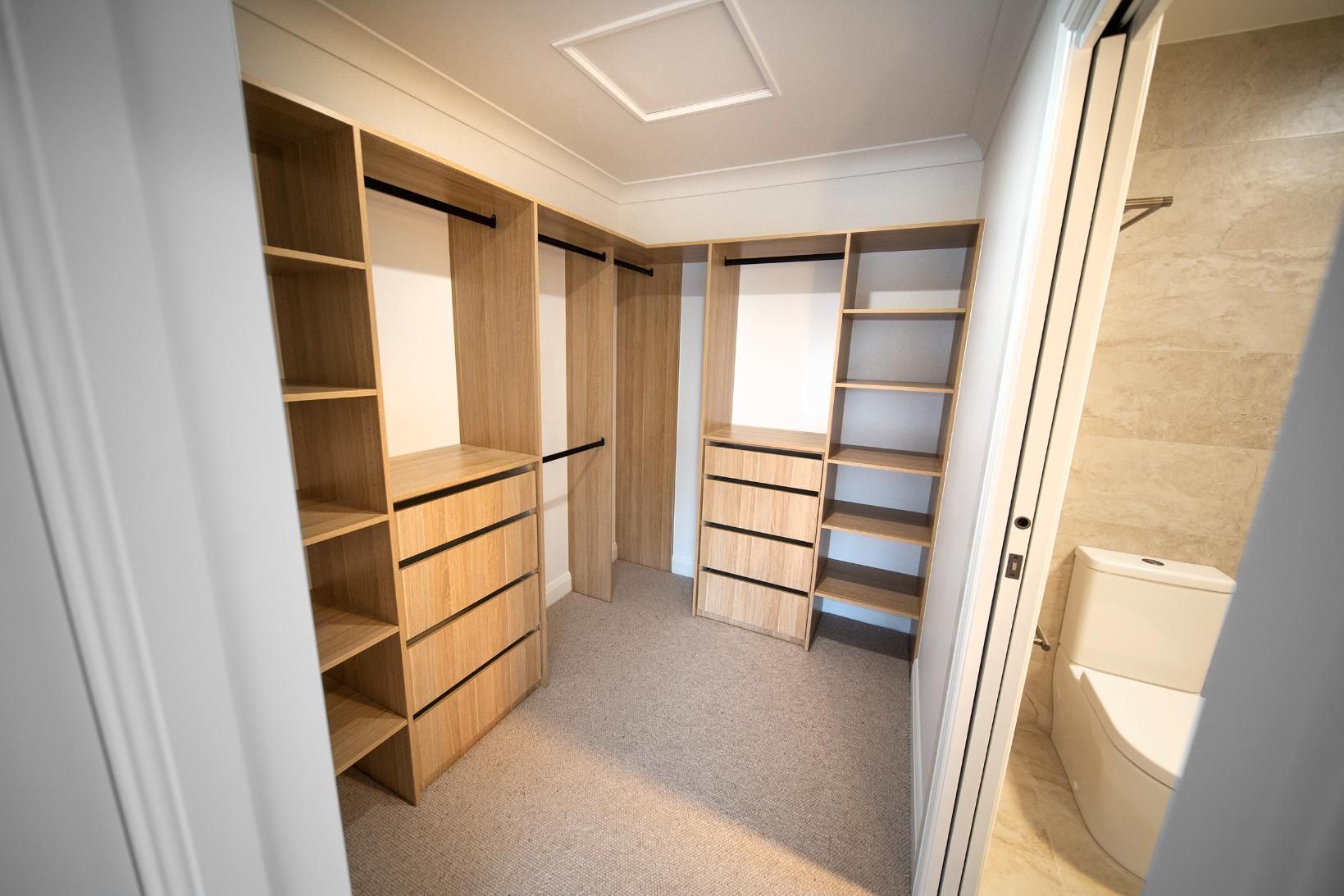 A Walk in Closet With Wooden Shelves and Drawers and a Toilet — Beach Breeze Building In Tumbi Umbi, NSW