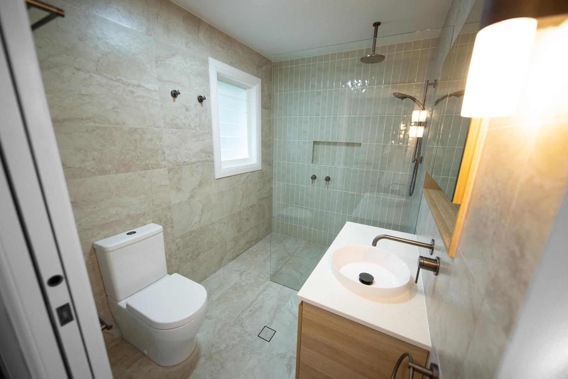 A Bathroom With a Toilet , Sink and Shower — Beach Breeze Building In Tumbi Umbi, NSW