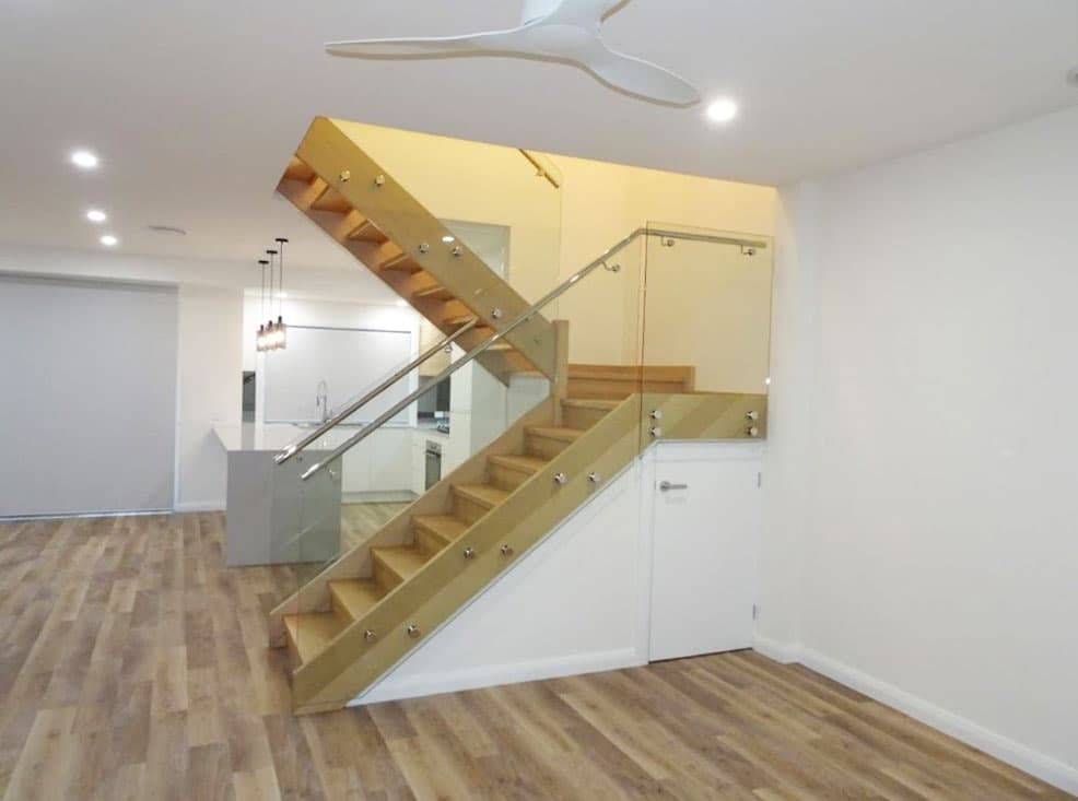 An Empty Room With A Wooden Staircase And A Glass Railing β Beach Breeze Building In Tumbi Umbi, NSW