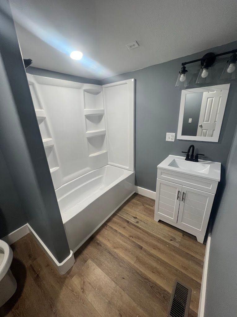 A bathroom with a bathtub , sink , mirror and toilet.