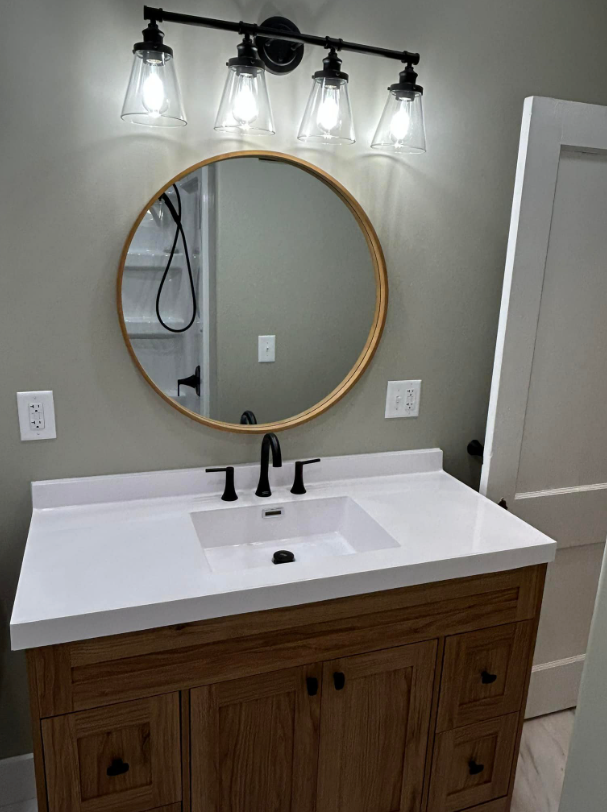 A bathroom with a sink , mirror and light fixture.