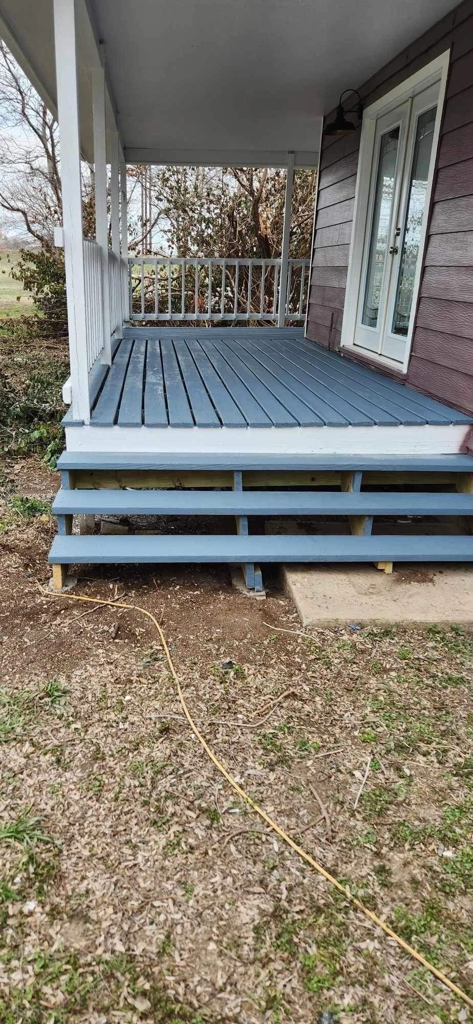 A porch with blue wooden steps and a white railing on a house.