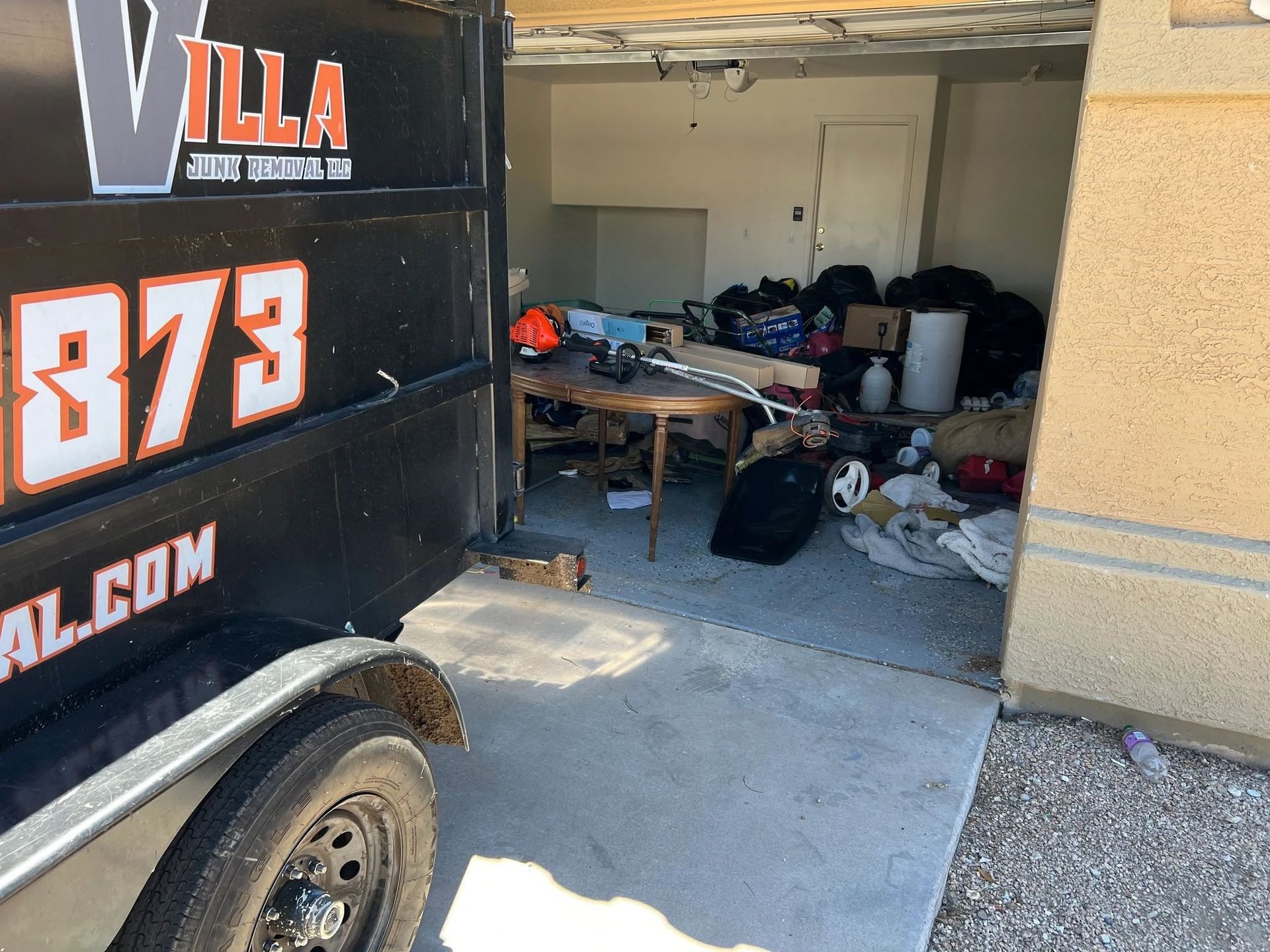 Moving truck beside an open garage filled with clutter and stored items
