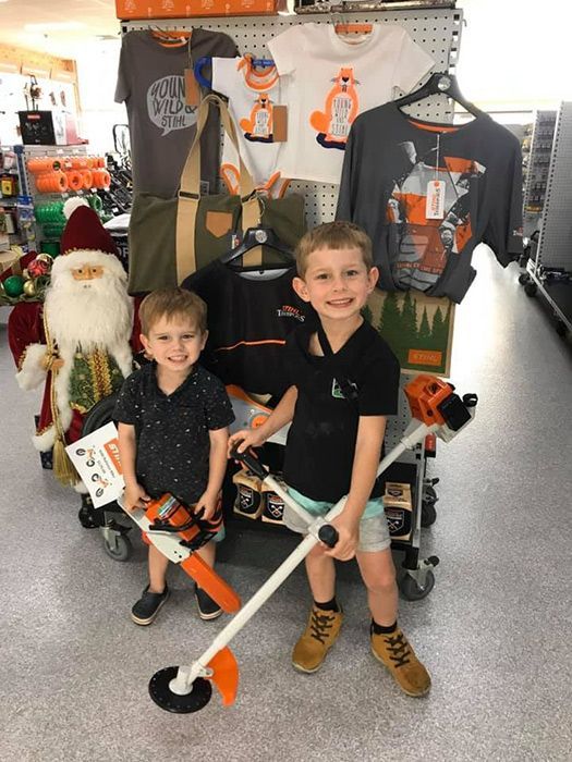 Two Young Boys Holding A Stihl Trimmer In A Store — Ken Matthews Auto & Mower Centre In Ulladulla, NSW