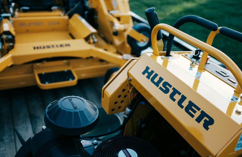 A Yellow Hustler Lawn Mower Is Parked Next To Another Yellow Lawn Mower — Ken Matthews Auto & Mower Centre In Ulladulla, NSW
