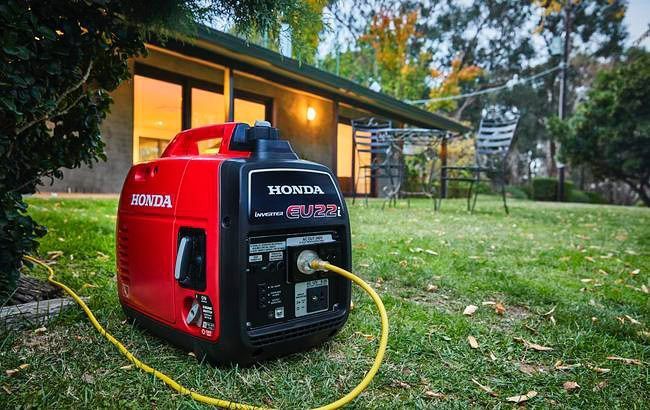 A Honda Generator Is Sitting In The Grass In Front Of A House — Ken Matthews Auto & Mower Centre In Ulladulla, NSW
