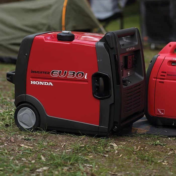 A Red Honda Generator Is Sitting In The Grass — Ken Matthews Auto & Mower Centre In Ulladulla, NSW