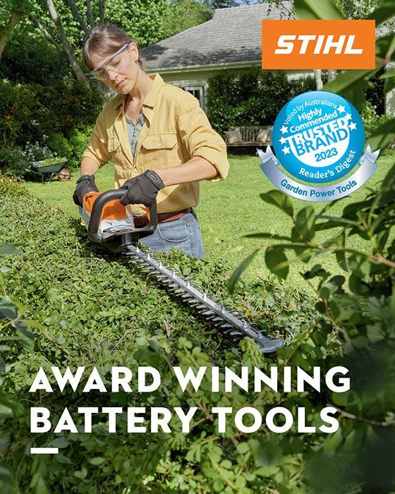 A Woman Is Cutting A Hedge With A Stihl Battery Hedge Trimmer — Ken Matthews Auto & Mower Centre In Ulladulla, NSW