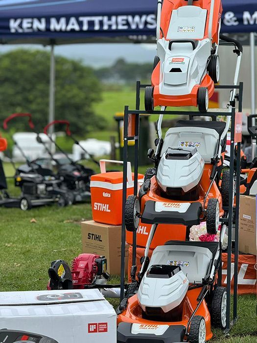 A Bunch Of Lawn Mowers Are Stacked On Top Of Each Other In A Field — Ken Matthews Auto & Mower Centre In Ulladulla, NSW