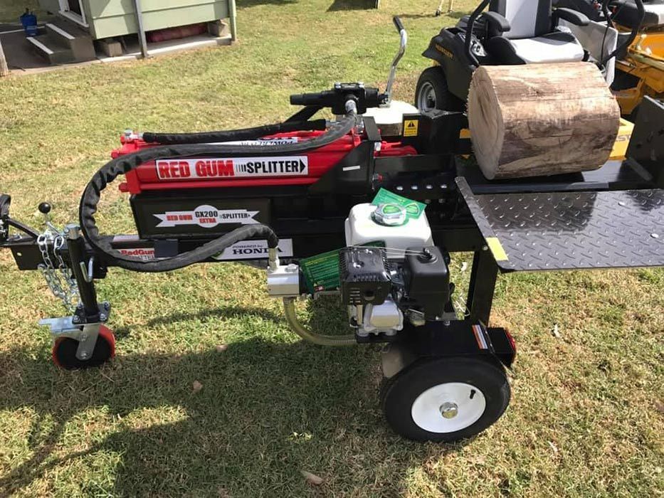 A Log Splitter Is Sitting On The Grass Next To A Lawn Mower — Ken Matthews Auto & Mower Centre In Ulladulla, NSW