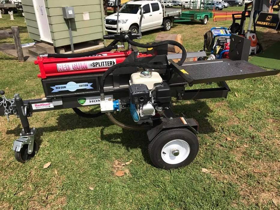 A Log Splitter Is Sitting On A Trailer In A Grassy Field — Ken Matthews Auto & Mower Centre In Ulladulla, NSW