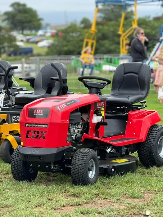 A Red Lawn Mower Is Parked In A Grassy Field — Ken Matthews Auto & Mower Centre In Ulladulla, NSW