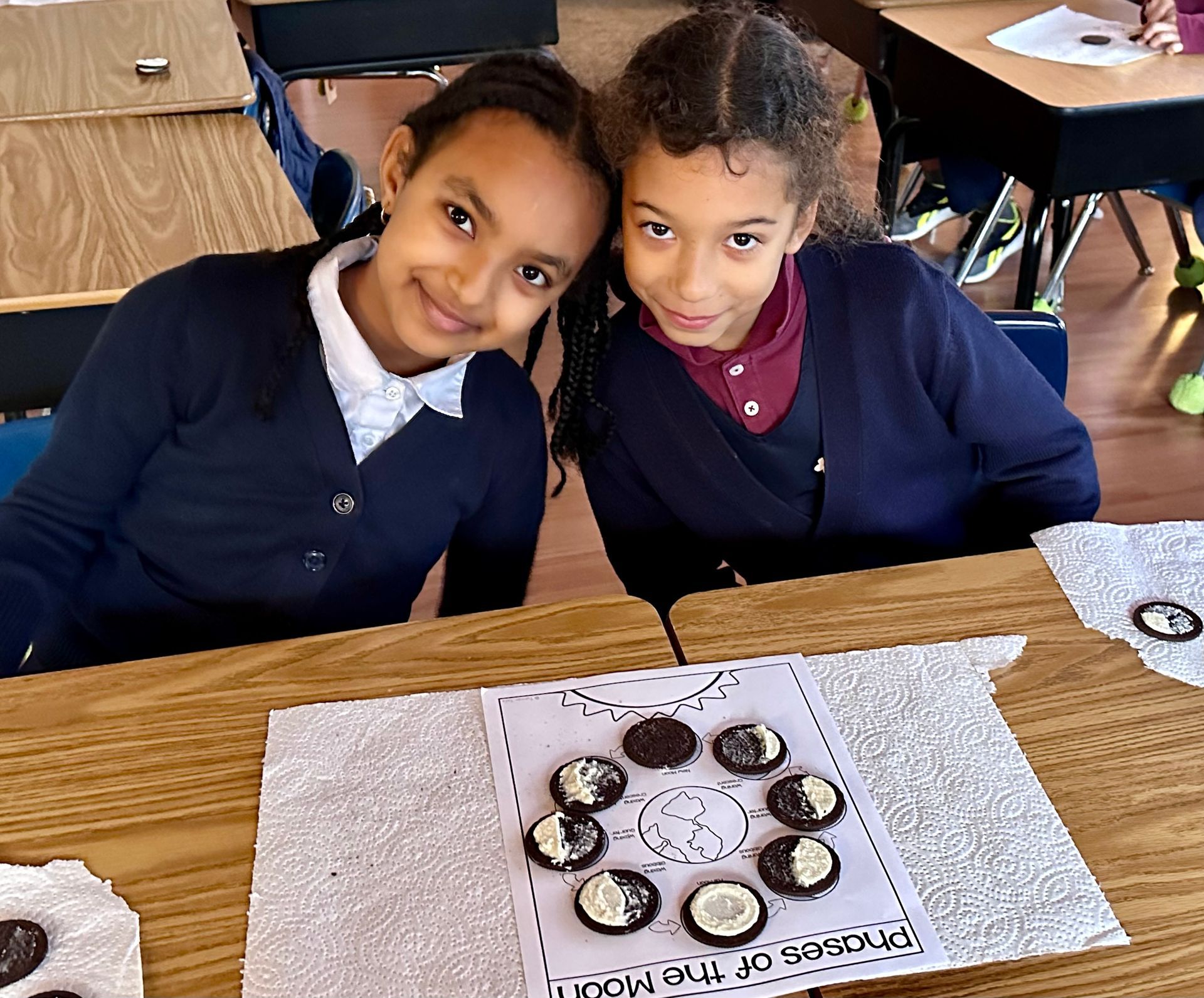 Two girls sit together while doing the phases of the moon activity.