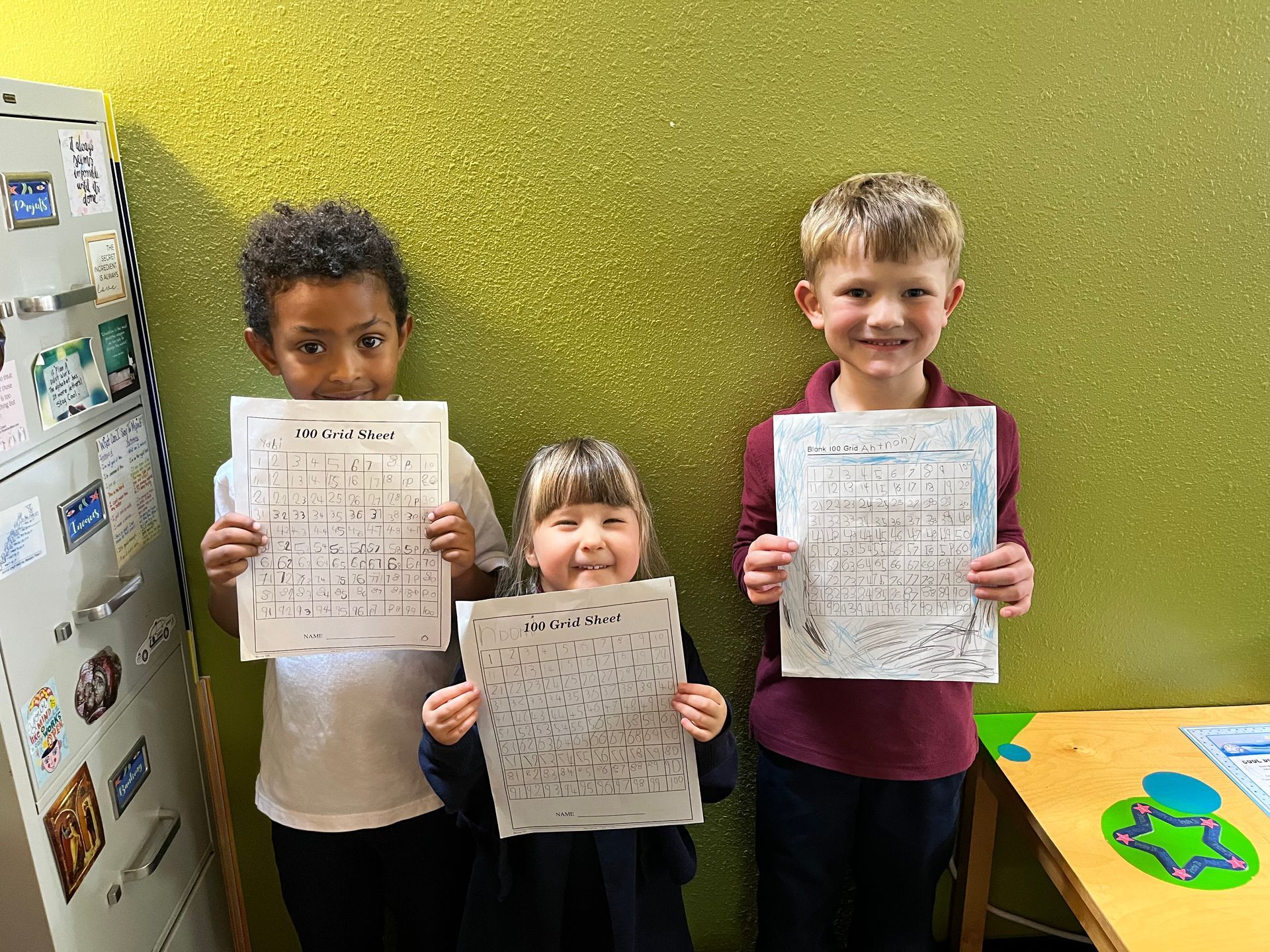 three kids showing their activity sheet