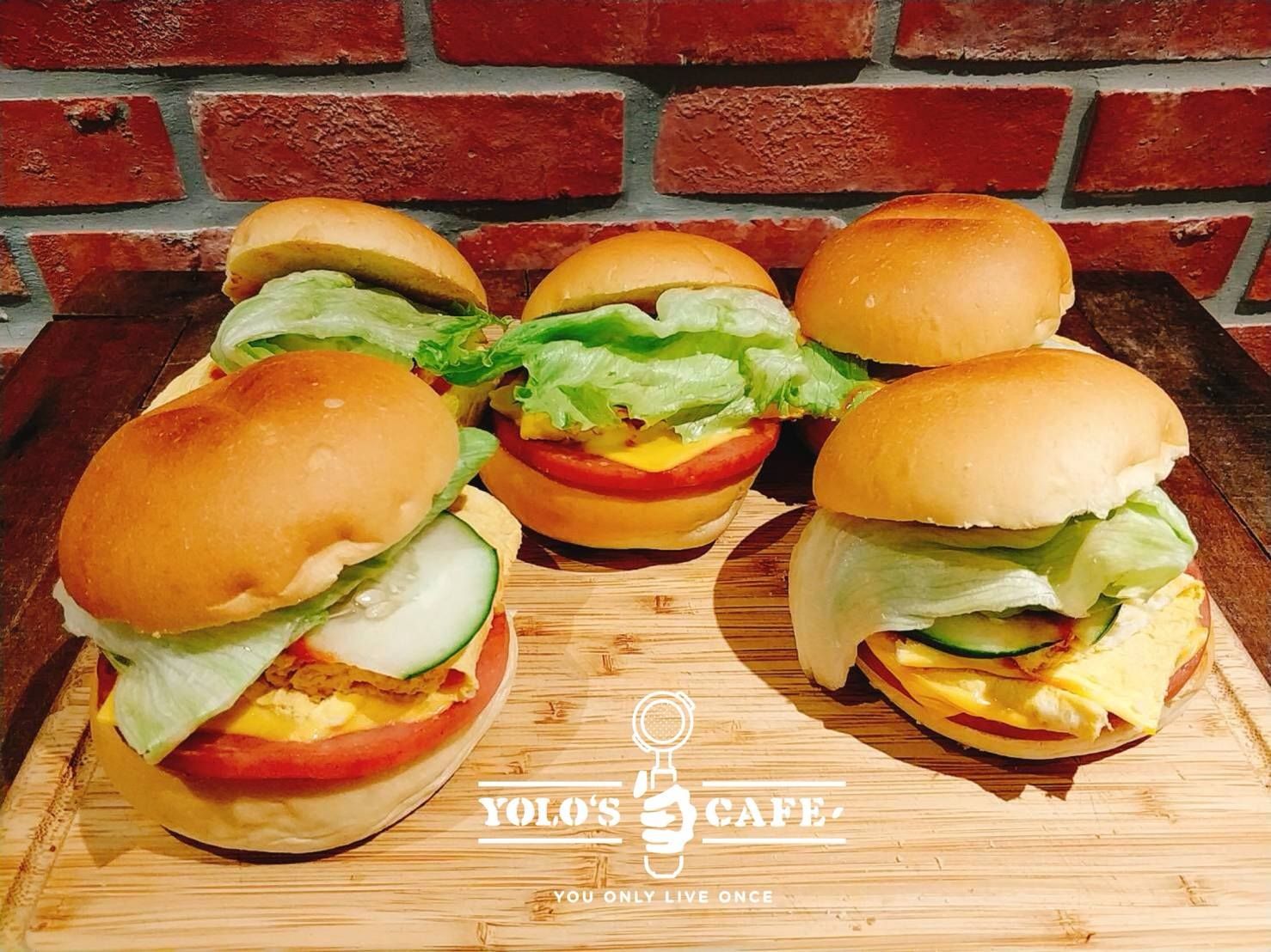 A bunch of hamburgers are sitting on a wooden cutting board.