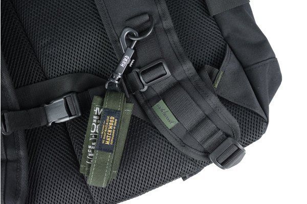 A black backpack with a green strap attached to it