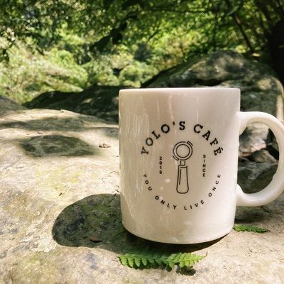 A white mug that says yolo 's cafe on it