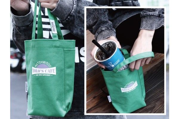A person is holding a cup in a green bag that says bob 's cafe