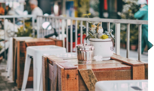 A wooden table with a white stool and a potted plant on it.
