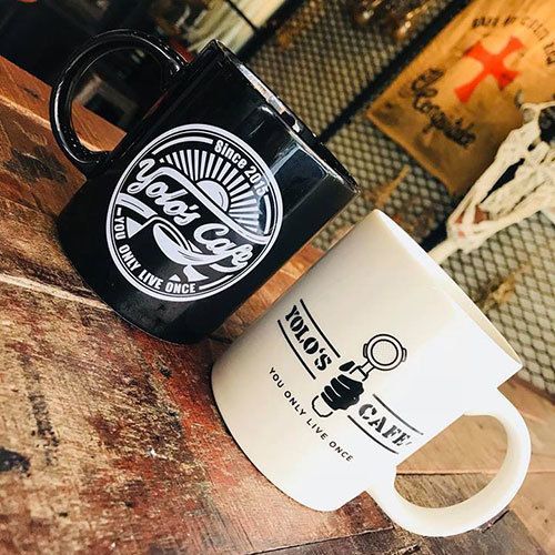 Two coffee mugs are sitting on a wooden table.